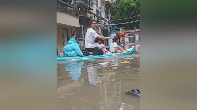 暴雨家长划桨板接娃引热议：极端天气下的另类接送方式